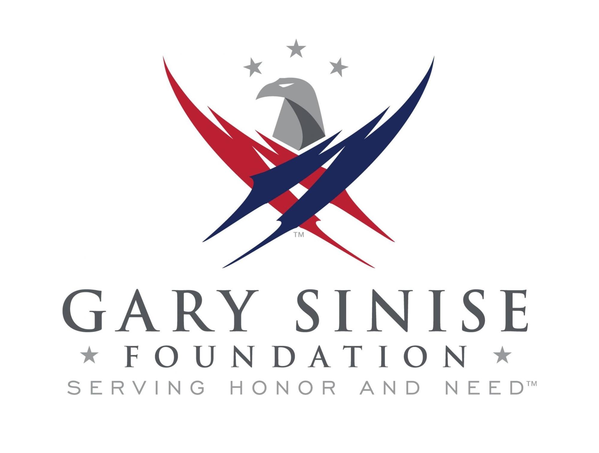 The Gary Sinise Foundation logo features a stylized gray eagle head centered above two intersecting, sweeping brushstroke-like wings&mdash;one red and one navy blue&mdash;forming an abstract patriotic emblem. Three gray stars are positioned in an arc above the eagle. Beneath the emblem, the organization's name, GARY SINISE FOUNDATION, appears in large gray serif lettering. Below that, the tagline "SERVING HONOR AND NEED&trade;" is displayed in smaller, light gray uppercase letters, separated by gray stars on either side. The logo is set against a white background and uses a patriotic color palette of red, white, blue, and gray.