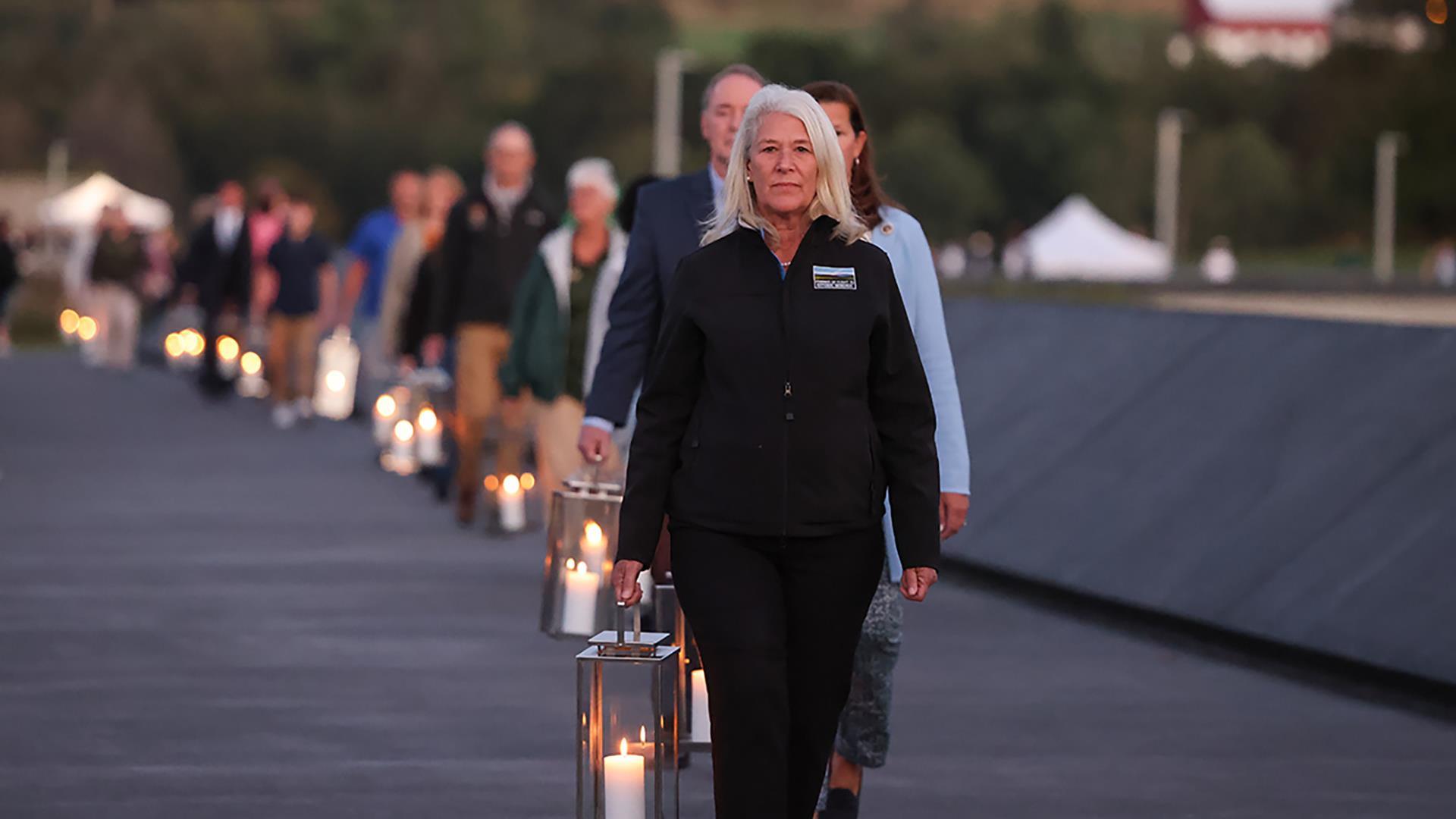 People walking on a path carrying lit lanterans.